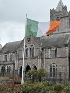 Irish flag flying in front of a historic stone church building in Ireland