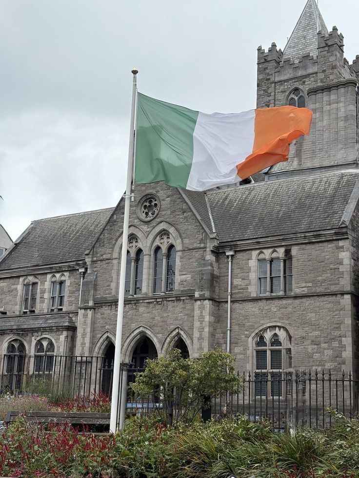 Irish flag flying in front of a historic stone church building in Ireland